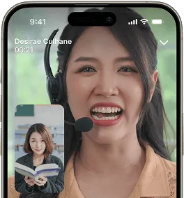 A woman wearing a headset speaks on a video call. The small inset shows the other participant, a woman holding an open book