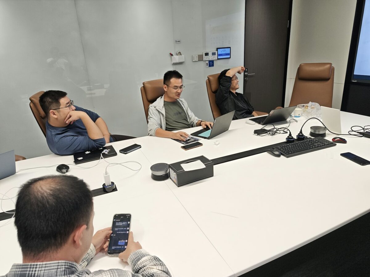 Four men in a meeting room with laptops