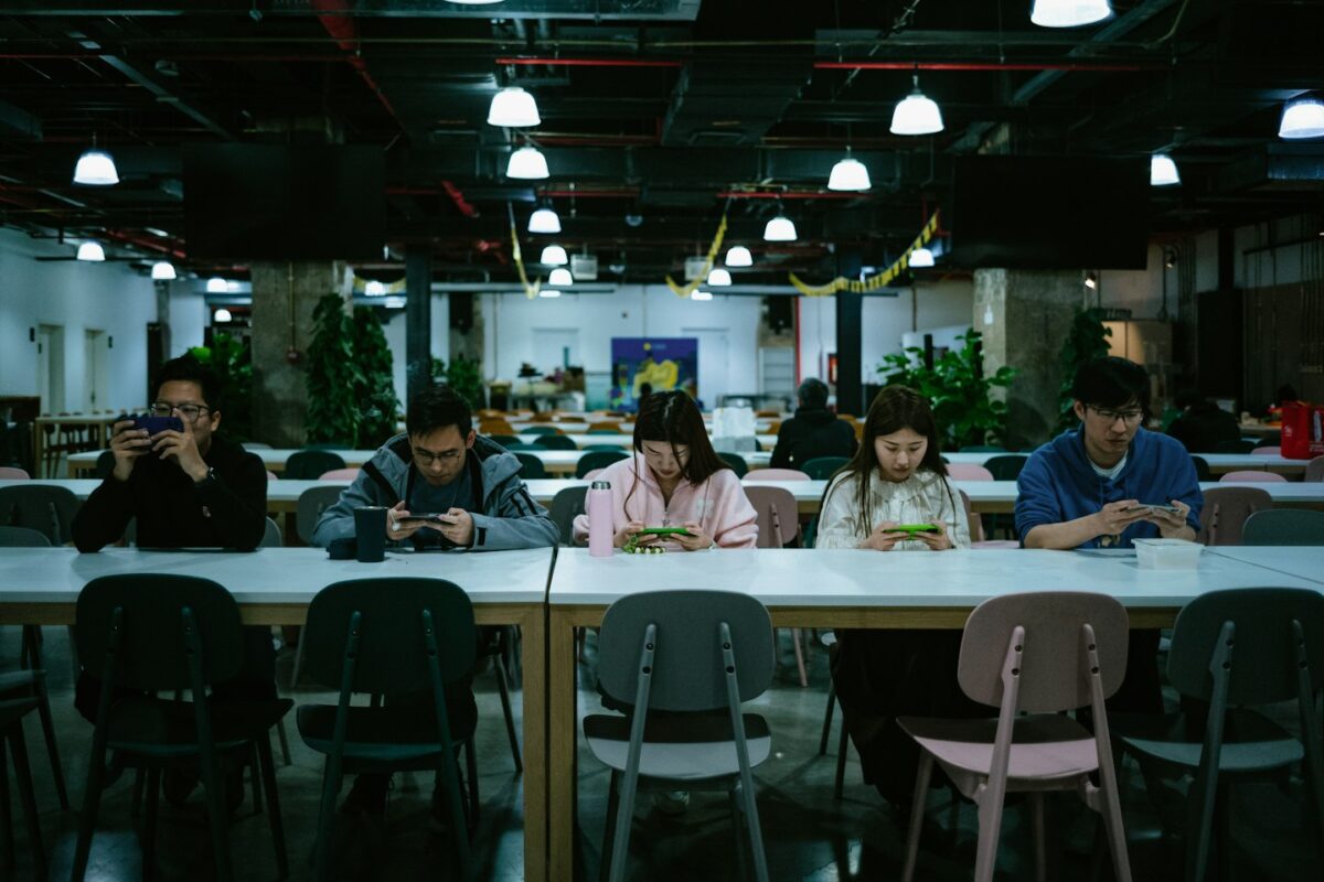 a group of people sitting at a table with cell phones