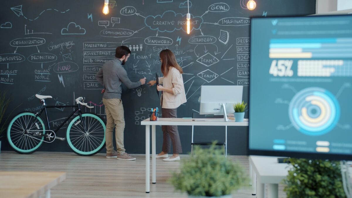 Two people collaborating on a chalkboard with a bicycle