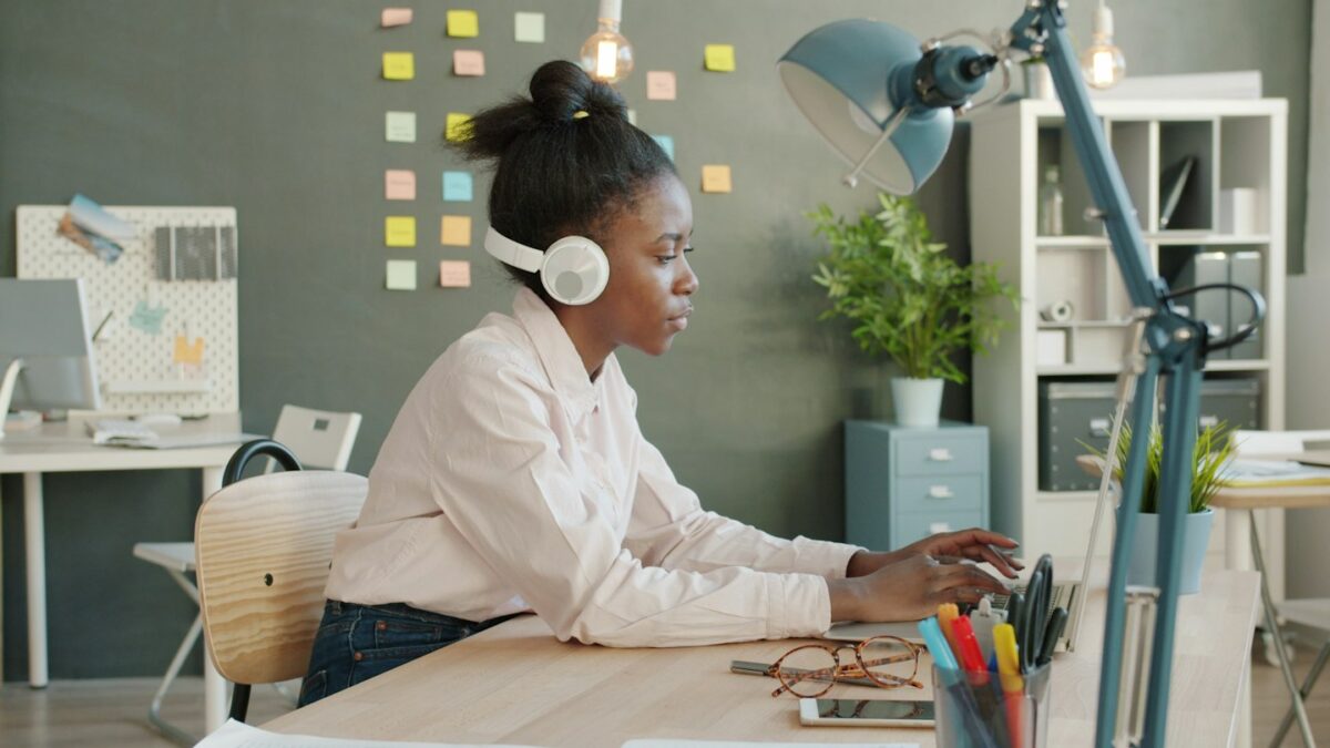 Woman wearing headphones working on laptop at desk