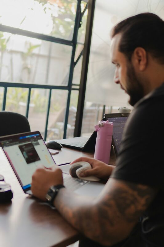 Man working on laptop with pink water bottle nearby