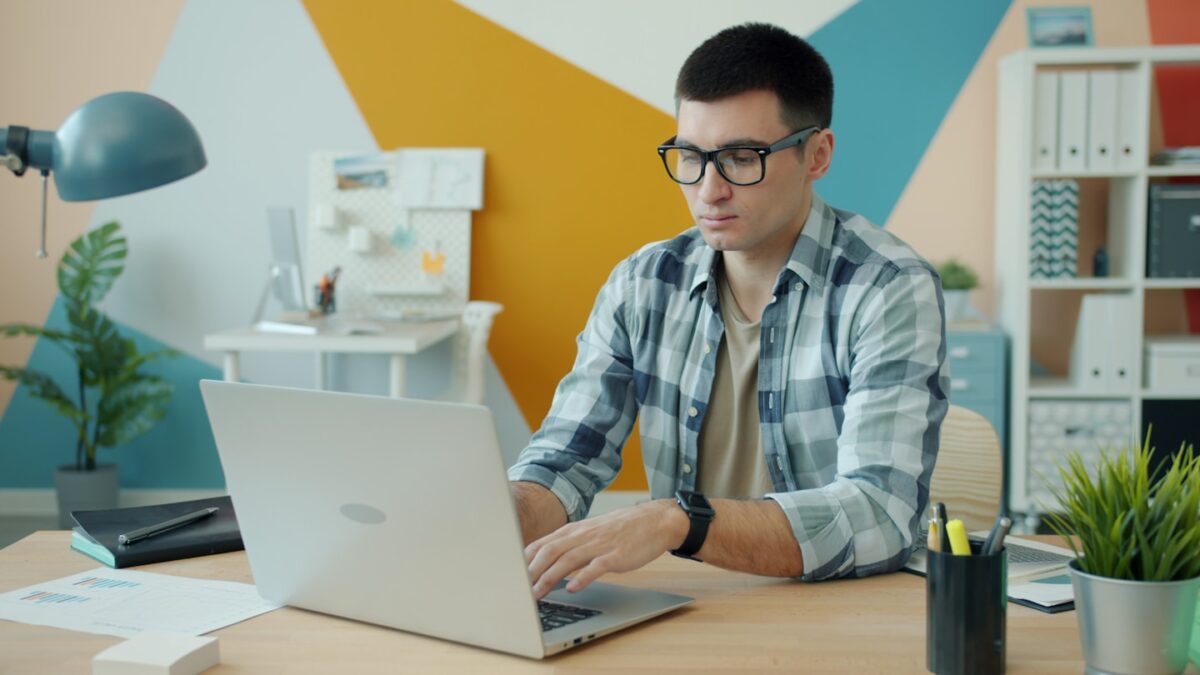 Man wearing glasses typing on a laptop at a desk