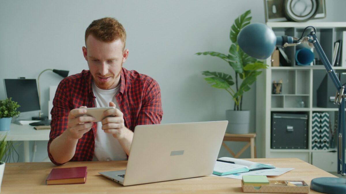 Man playing a video game on his phone at desk