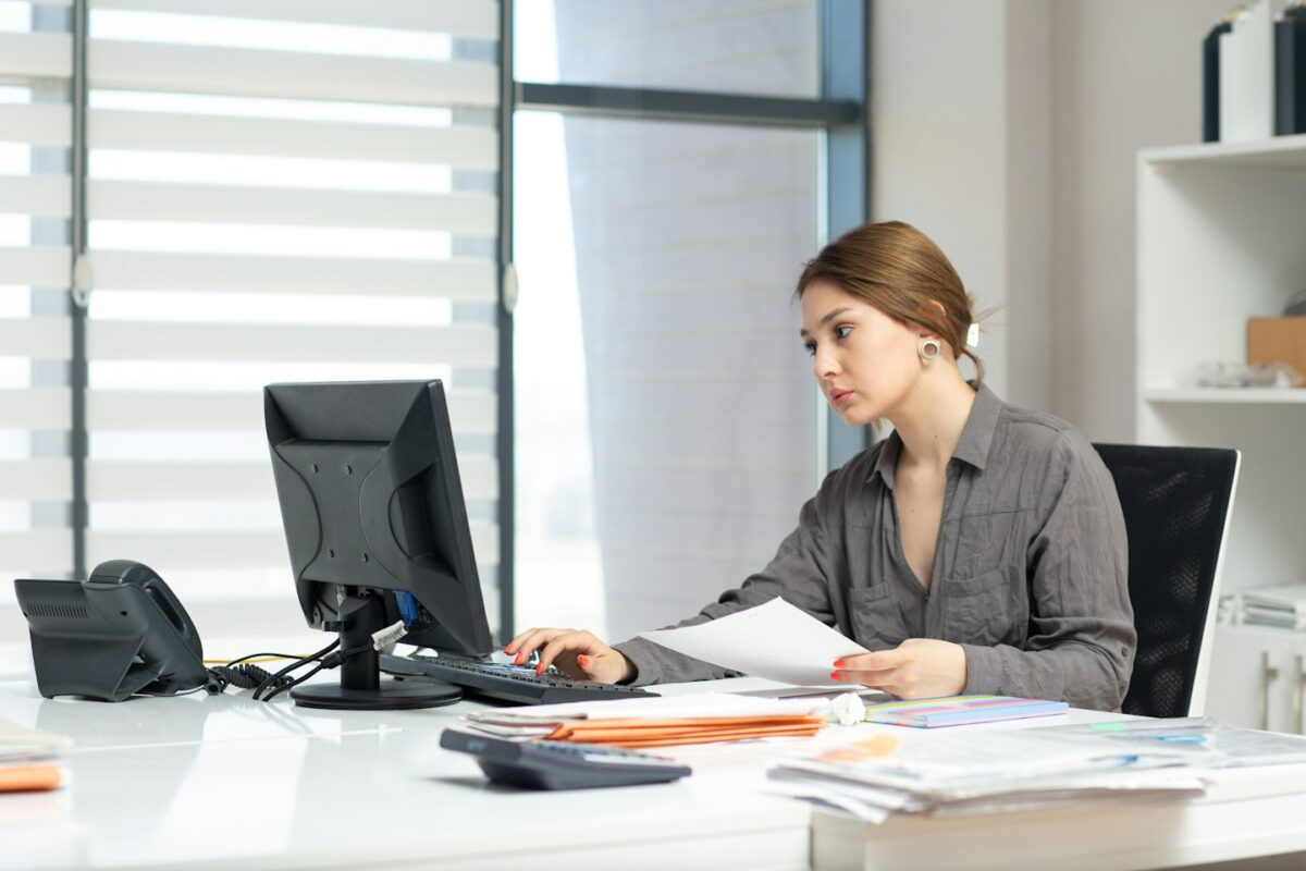Young woman focused on computer and documents at office desk